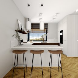 Cozy Studio - Jasna kuchnia z wyspą i trzema hokerami. Parkiet w jodełkę, minimalistyczne lampy wiszące. Okno z żaluzjami w tle. Nowoczesny design, neutralna kolorystyka.