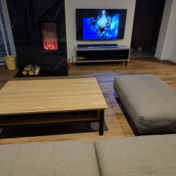 HIMEBLE SPÓŁKA Z OGRANICZONĄ ODPOWIEDZIALNOŚCIĄ - Nowoczesny salon z drewnianą podłogą, kominkiem z czarnego marmuru, telewizorem i stolikiem kawowym z jasnego drewna.
