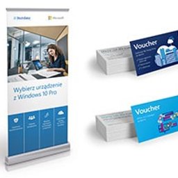 Agencja Reklamowa Motive Marek Pisarik - Roll-up reklamowy z hasłem 'Wybierz urządzenie z Windows 10 Pro', wizytówki ułożone w stosy oraz dwie pojedyncze wizytówki z motywem voucherów w kolorach niebieskim i białym.