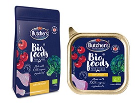 Opakowania karmy dla psów marki Butcher's Bio Foods: zamknięta torba z niebieskim tłem, grafiką pomidorów i brokułów oraz puszką karmy z podobną grafiką, obie z logo marki i informacją...