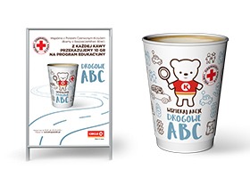 Stojak reklamowy z plakatem i kubek z nadrukiem promujące program edukacyjny 'Drogowe ABC' z logo Polskiego Czerwonego Krzyża i Circle K, przedstawiające białego misia z czerwoną koszulką...