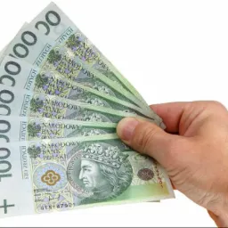 Dłoń trzymająca wachlarz banknotów 100 zł na białym tle.