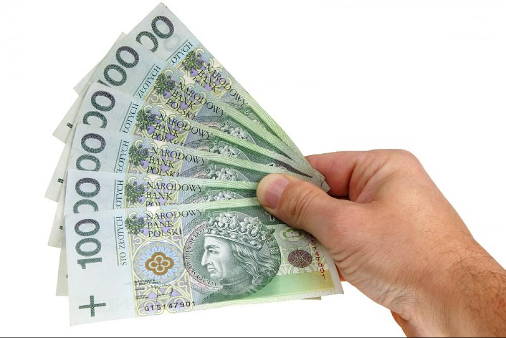 Dłoń trzymająca wachlarz banknotów 100 zł na białym tle.