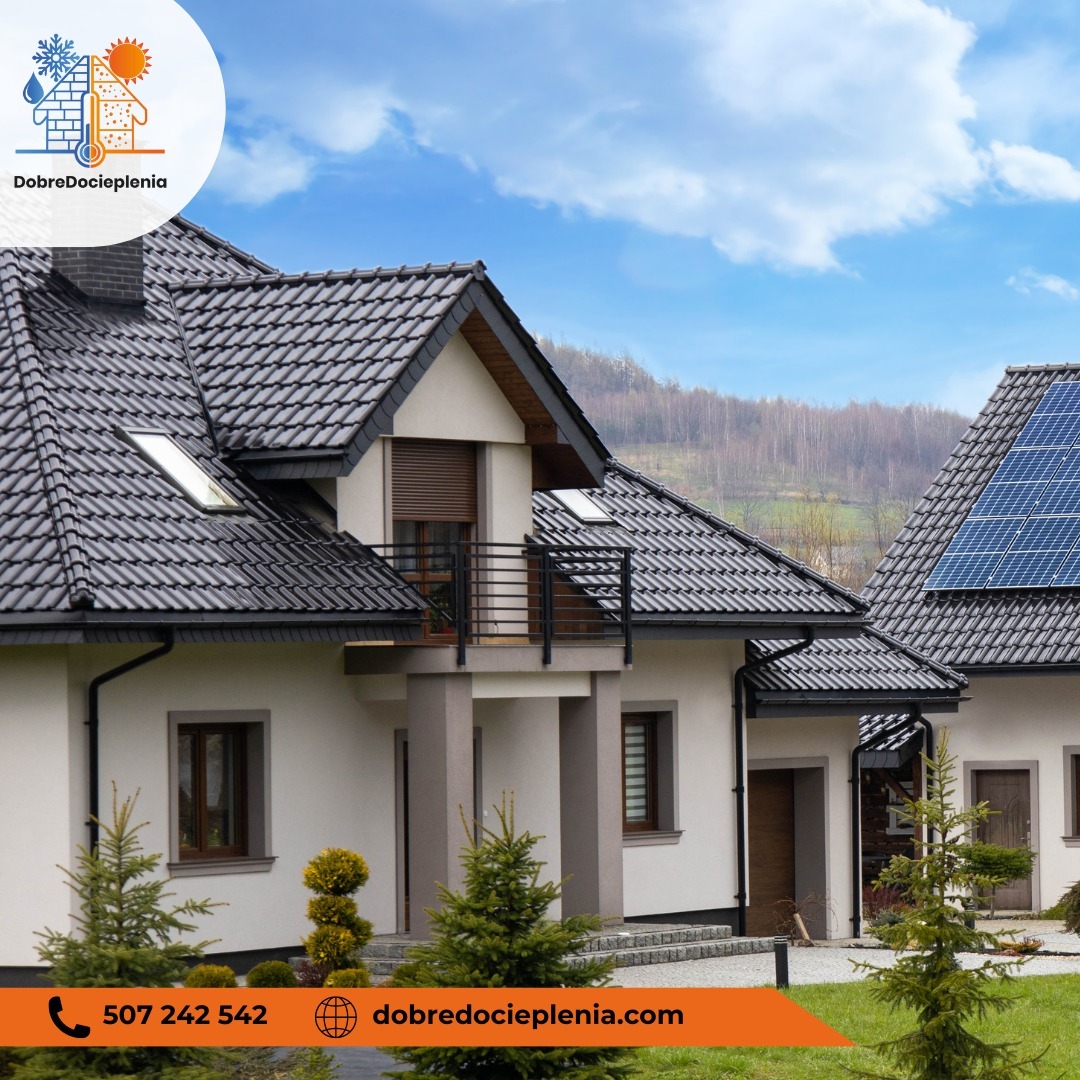 Dwa domy jednorodzinne z jasną elewacją, ciemną dachówką, jeden z panelami słonecznymi na dachu, mały balkon z czarną balustradą, zadbany ogród z iglakami na pierwszym planie, błękitne niebo w tle.