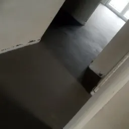 Świeżo wylana, ciemnoszara posadzka w surowym wnętrzu z widocznym oknem w tle.