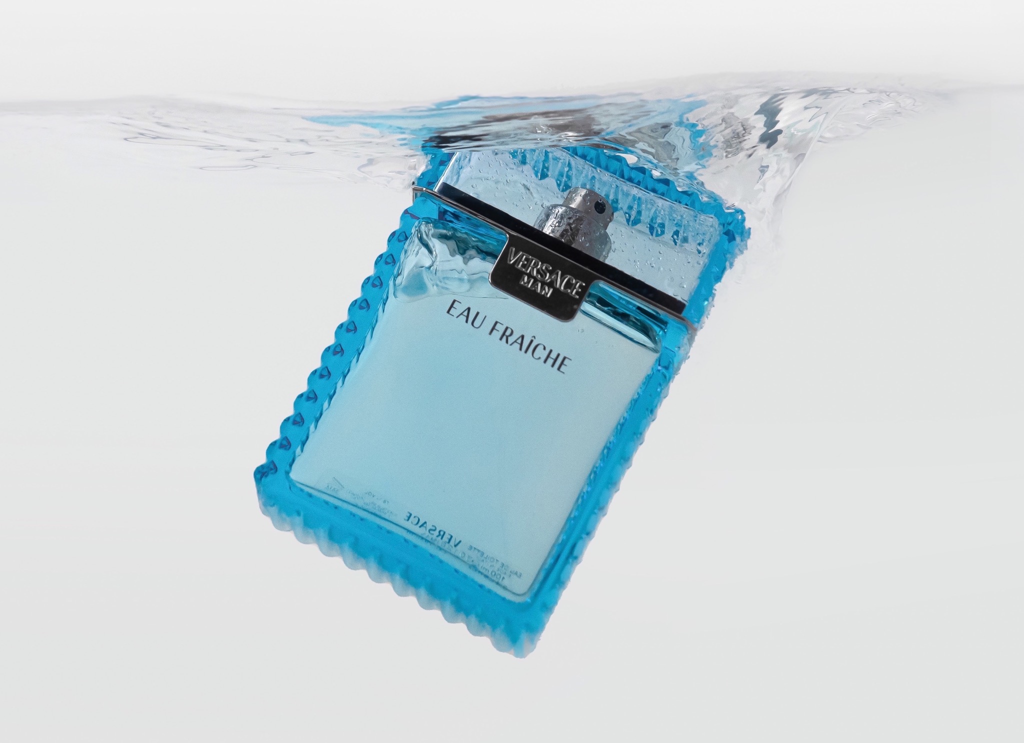 Flakon perfum Versace Eau Fraiche zanurzony w wodzie, z widocznymi kroplami i załamaniami światła.