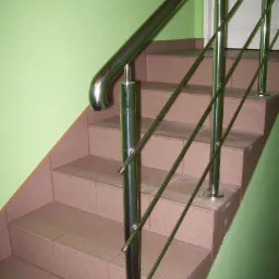 Polerowana, stalowa poręcz schodowa z poziomymi prętami, zamontowana przy schodach wyłożonych brązowymi płytkami w budynku w Warszawie.