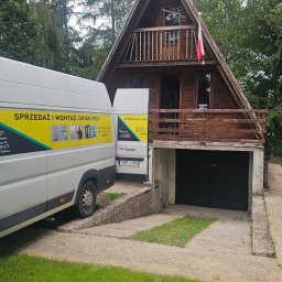 RAJPLAST SYLWIA RAJCHERT - Montaż okien PCV w drewnianym domu typu A-frame, widoczny samochód dostawczy z reklamą firmy.