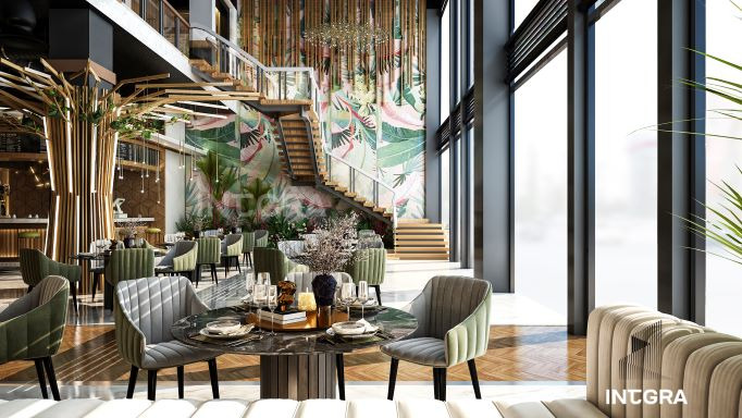 Wnętrze restauracji z wysokim sufitem, schodami, roślinnym motywem na ścianie i dekoracyjnymi elementami imitującymi drzewa, zaaranżowane stoliki z nakryciami i krzesłami w odcieniach zieleni...