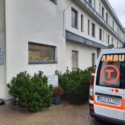 Ambulans zaparkowany przed budynkiem kliniki wentylacji respiratorami, widoczny znak NFZ
