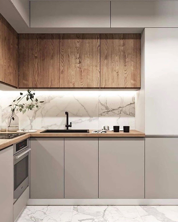 Nowoczesna kuchnia z szarymi frontami szafek dolnych i drewnianymi szafkami wiszącymi, czarna armatura, marmurowy backsplash i podświetlenie LED pod szafkami wiszącymi. Na blacie widoczne czarne...