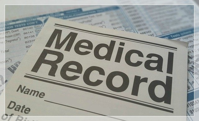 Zbliżenie na formularz medyczny z polami do wypełnienia, leżący na arkuszach z wynikami badań laboratoryjnych.