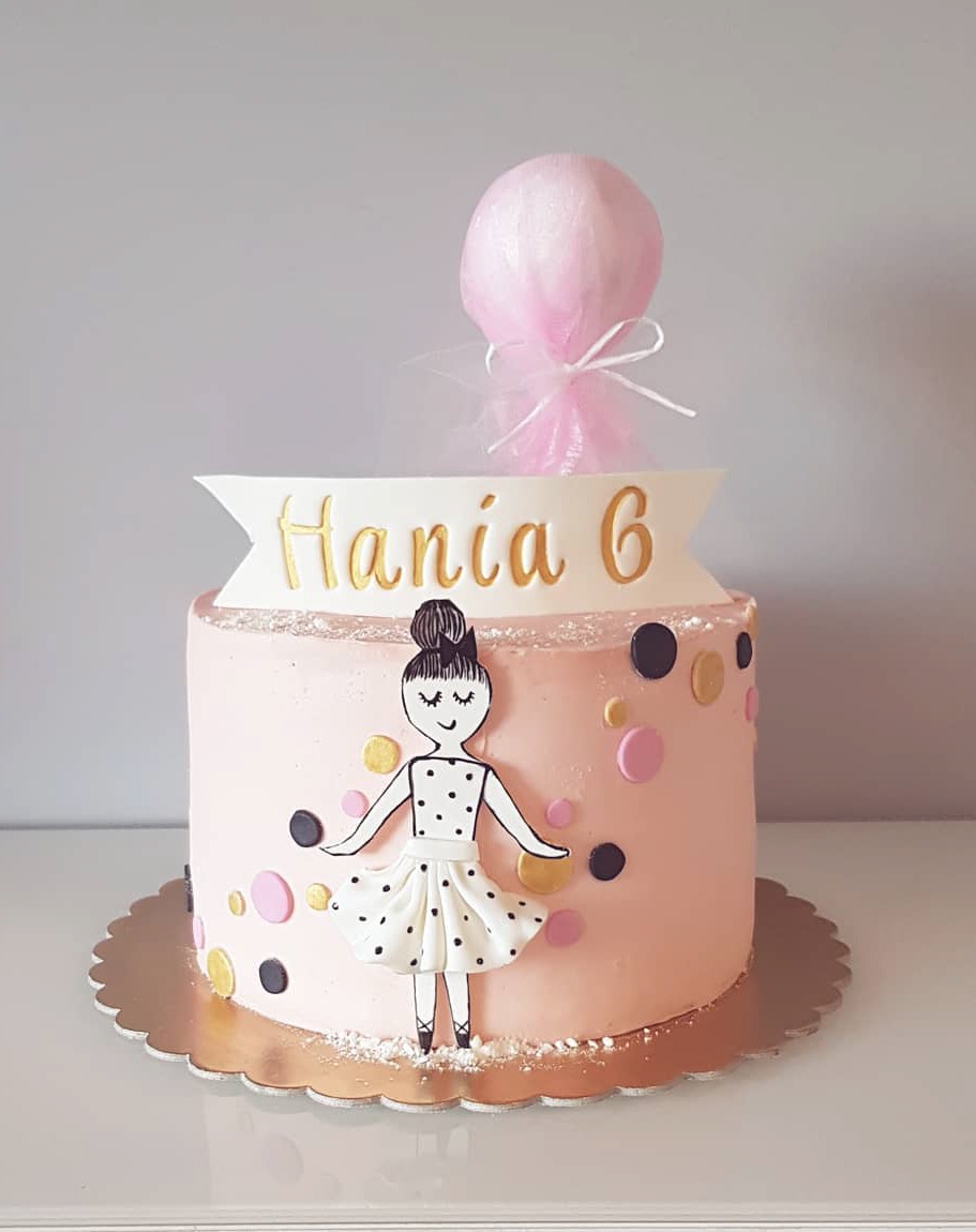 Tort urodzinowy w Gdańsku z różowym lukrem, dekoracją baletnicy i napisem 'Hania 6' w złotym kolorze, zwieńczony różową watą cukrową.