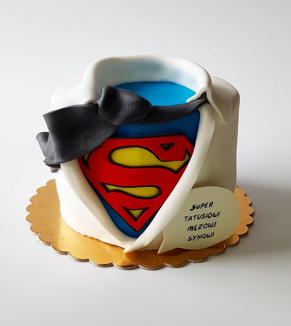 Tort w kształcie koszuli z logiem Supermana i napisem 'Super Tatusiowi Mężowi Synowi', na złotej podkładce.