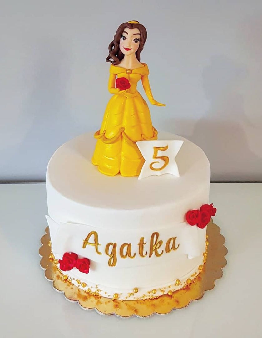 Tort urodzinowy z figurką księżniczki w żółtej sukni, dekorowany imieniem 'Agatka', cyfrą '5' i czerwonymi różami.