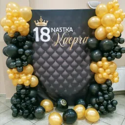 Dekoracja balonowa w kolorach czarnym i złotym z okazji 18 urodzin, z czarnym tłem z napisem '18 Nastka Kacpra' i koroną.