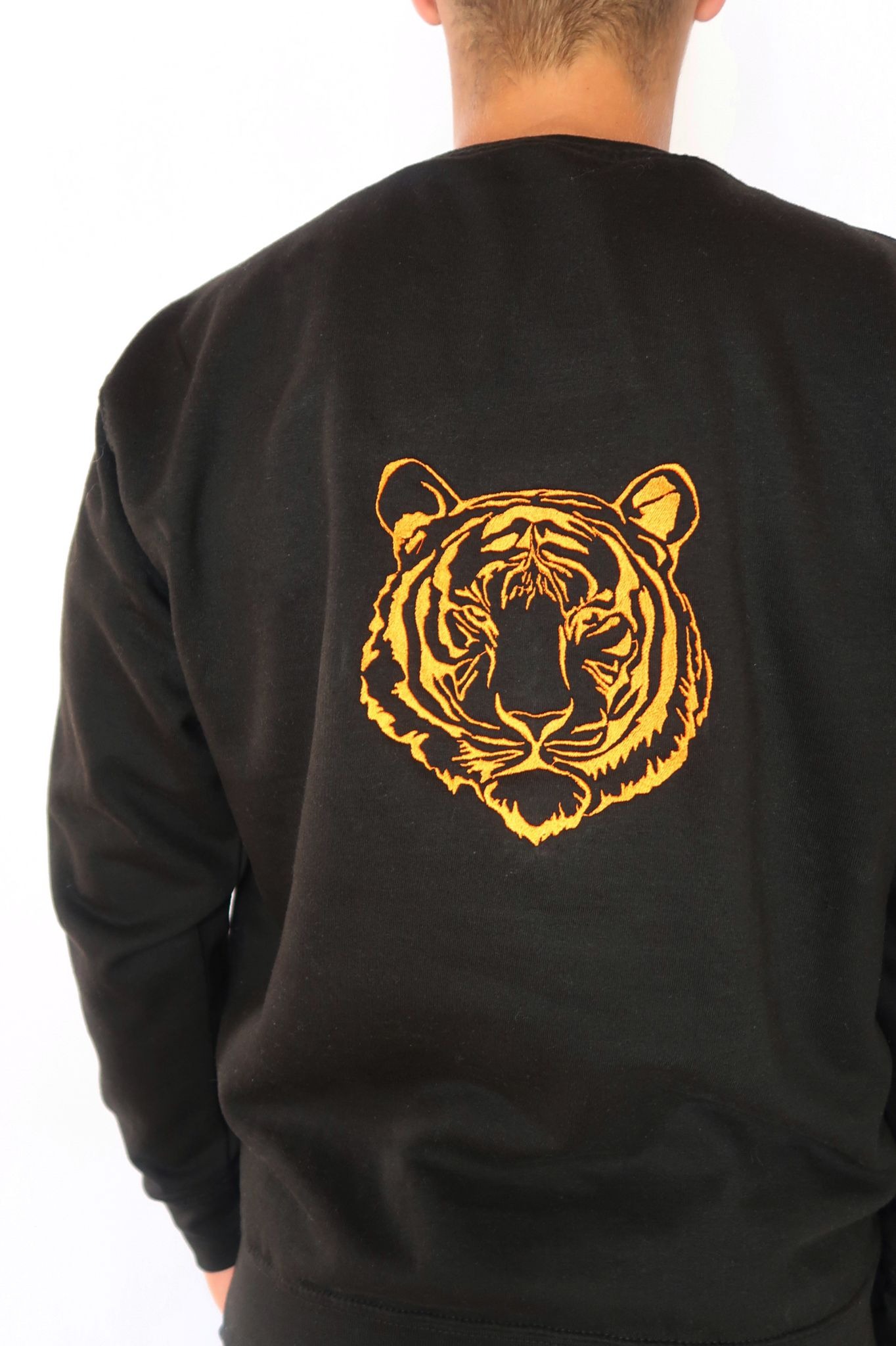 Czarna bluza z haftowanym pomarańczowym motywem tygrysa na plecach, widok z tyłu.