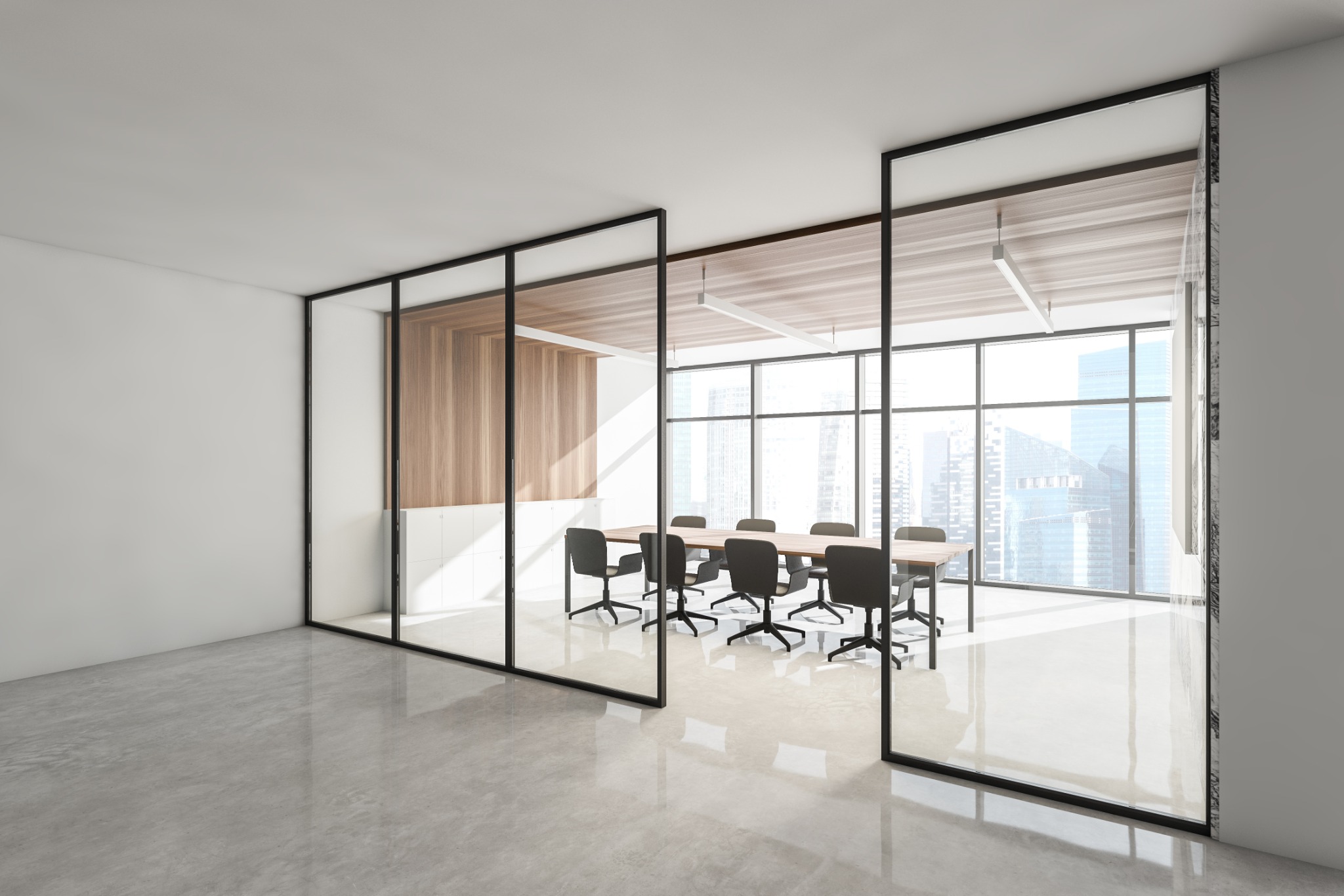 Nowoczesna sala konferencyjna z przeszklonymi ścianami w czarnych ramach, widok na miasto za oknami, drewniany stół otoczony krzesłami na kółkach, polerowana betonowa podłoga.
