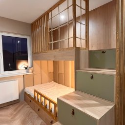 Cool-Ka MEBLE - Pokój dziecięcy z drewnianym łóżkiem na antresoli, zabezpieczonym siatką sznurkową, z wejściem po schodach będących jednocześnie szafkami. Beżowe panele tapicerowane na ścianie za łóżkiem, parkiet...