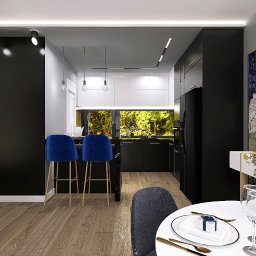 LS Interiors - Nowoczesna kuchnia z czarnymi szafkami, marmurowym blatem i oknem z widokiem na zieleń, uzupełniona o wysokie, aksamitne, niebieskie hokery i stół z elegancką zastawą oraz kwiatami.