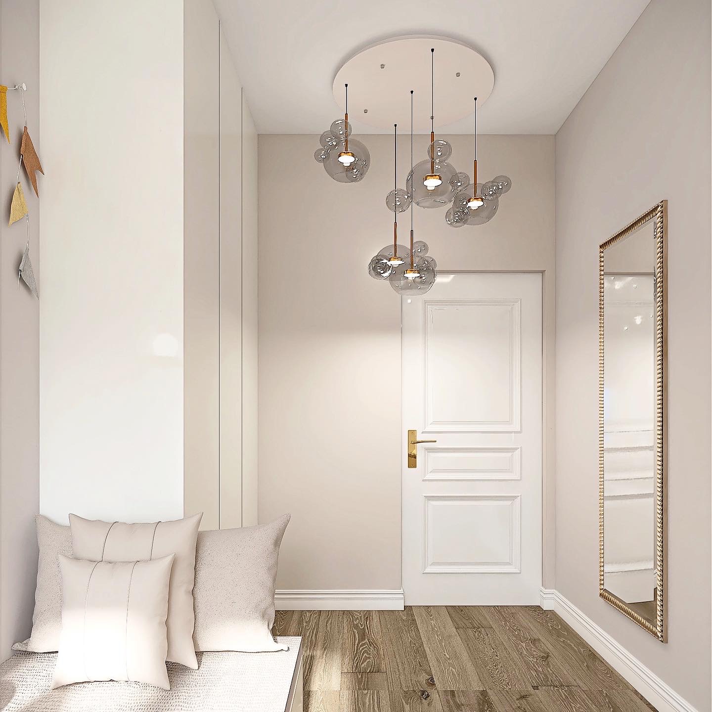 Nowoczesny przedpokój z drewnianą podłogą, białymi ścianami, lustrem w złotej ramie, wbudowaną szafą, siedziskiem z poduszkami w odcieniach beżu oraz designerską lampą sufitową z przezroczystymi...