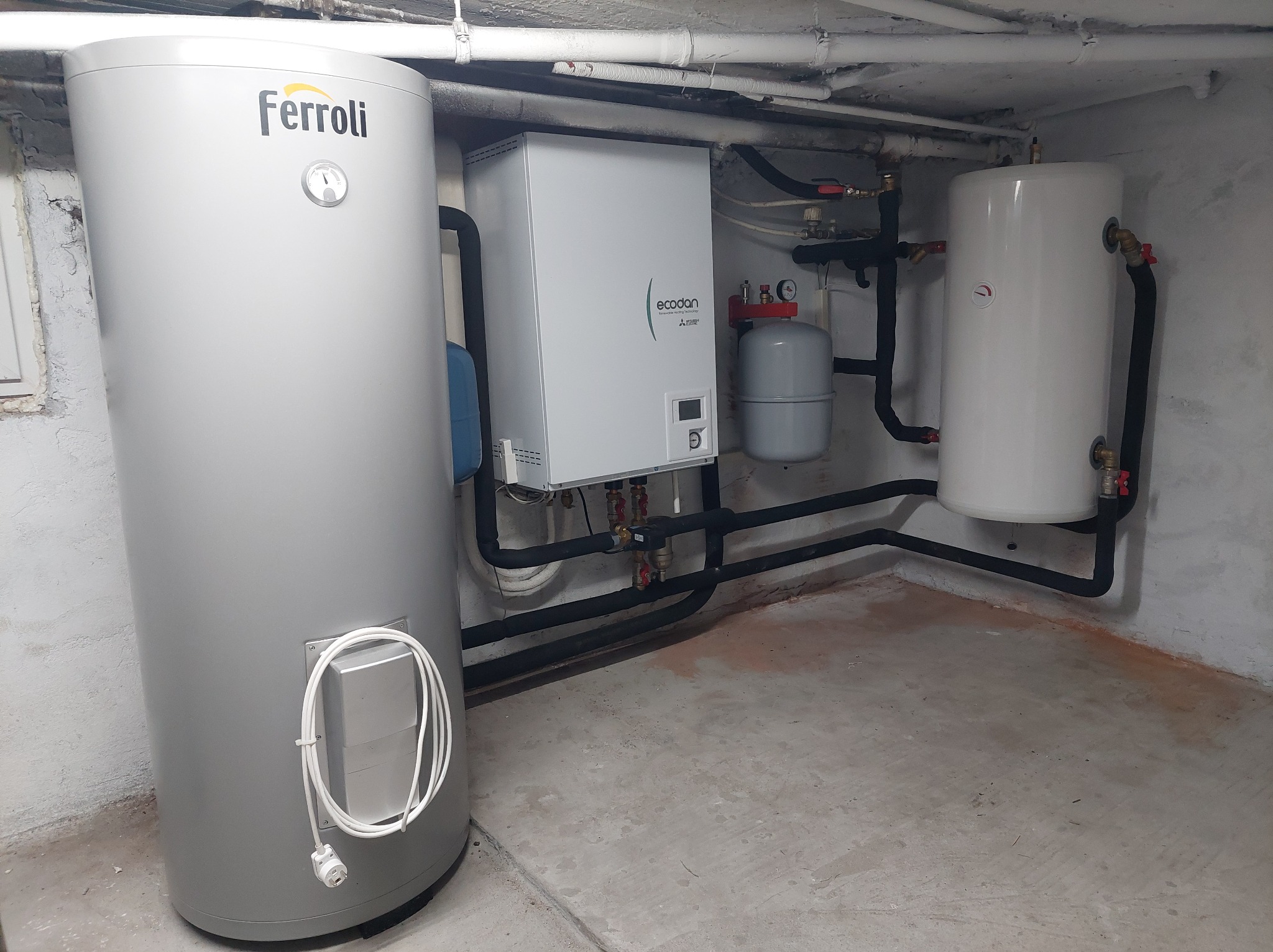 Instalacja pompy ciepła Ecodan i zasobnika Ferroli w piwnicy w Częstochowie, widoczne rury i zawory.