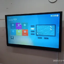 Interaktywny monitor dotykowy marki Newline zamontowany na ścianie, wyświetlający ekran główny z ikonami aplikacji.