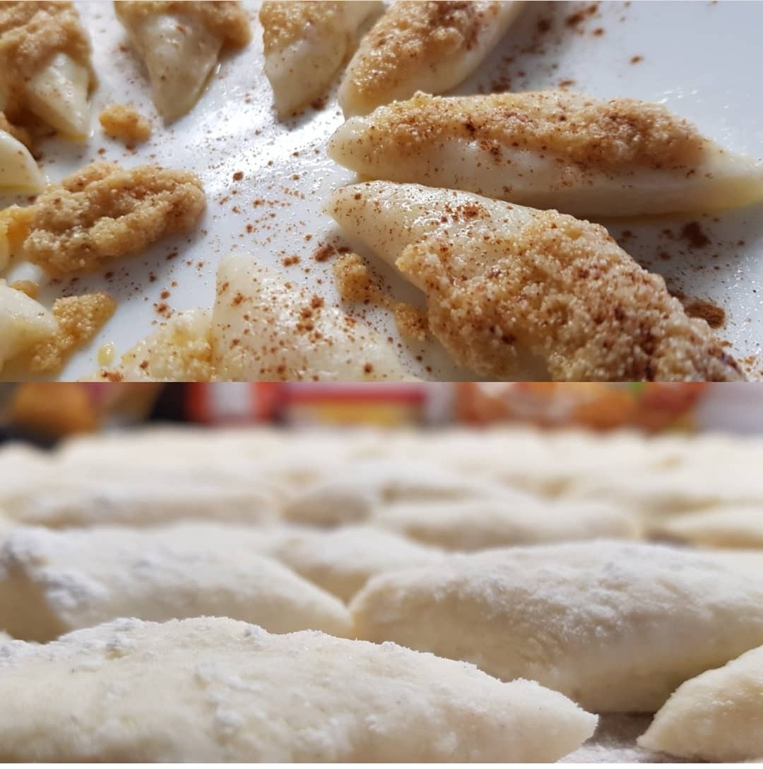 Kluski leniwe posypane bułką tartą i cynamonem na białym talerzu, w dolnej części kadru surowe kluski obtoczone w mące.
