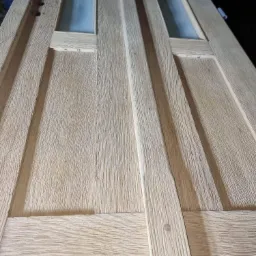 Drewniane drzwi z dwoma przeszkleniami, poddane obróbce szczotką, ukazujące wyraźną strukturę drewna.