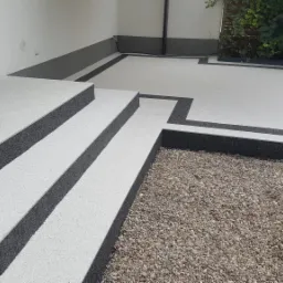 Wykończony taras z schodami z jasnej powierzchni z ciemnymi obramowaniami, widok z góry na zewnątrz budynku.