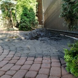 ProExtreme Tomasz Szempliński - Brudna kostka brukowa i elewacja budynku po umyciu, z widocznymi zaciekami i pozostałościami błota. Na pierwszym planie czysta kostka, w tle sterta brudu i kałuża.