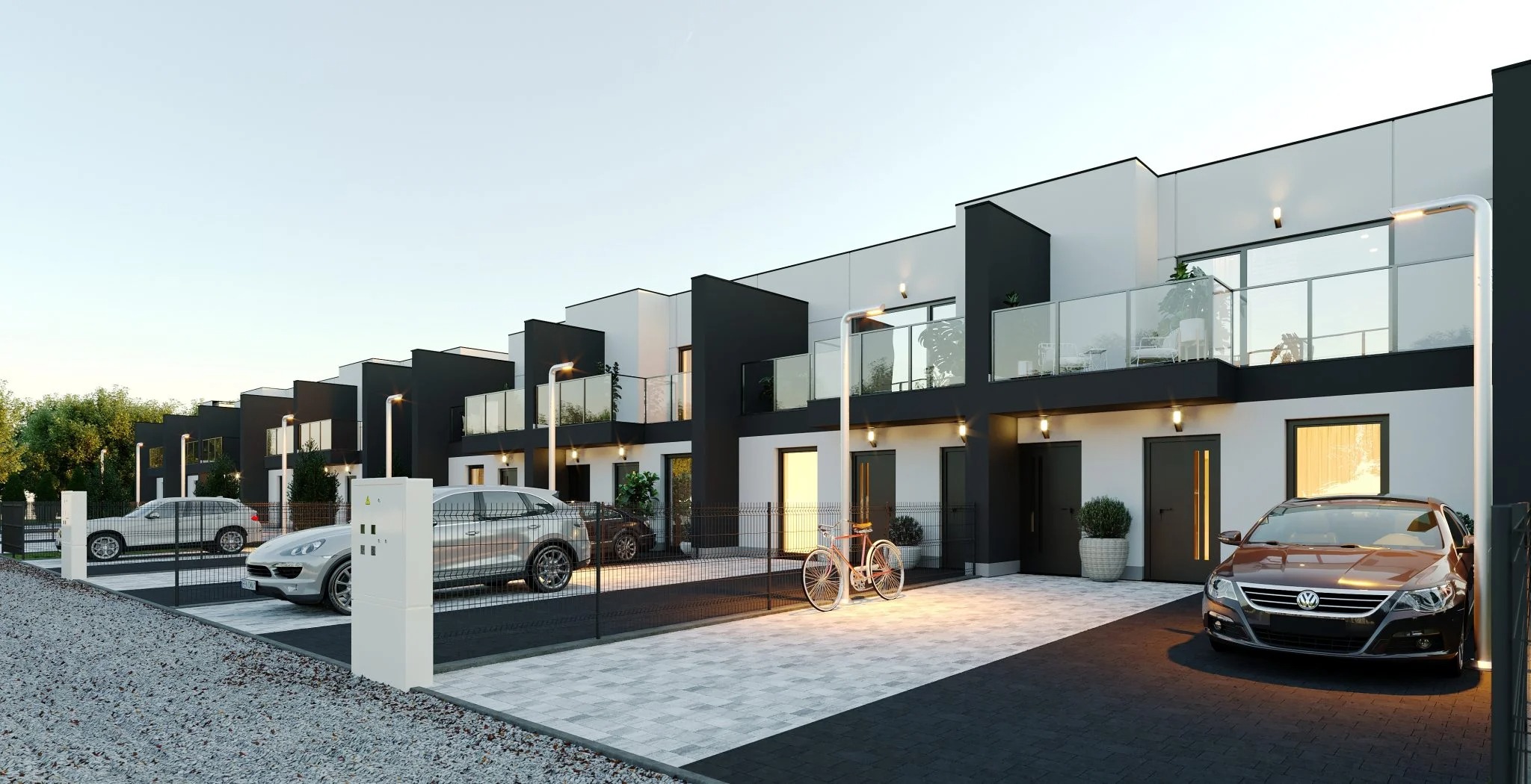Szereg nowoczesnych domów z balkonami, otynkowanych na biało z czarnymi elementami, ogrodzonych metalową siatką, z zaparkowanymi samochodami i rowerem.