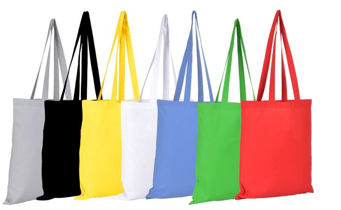Sześć materiałowych toreb na zakupy w kolorach: szary, czarny, żółty, biały, błękitny i czerwony, ustawione obok siebie na białym tle.