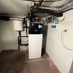 Projekt Instal - Zainstalowana pompa ciepła Daikin w piwnicy, widoczne rury, zbiornik buforowy i skrzynka elektryczna.