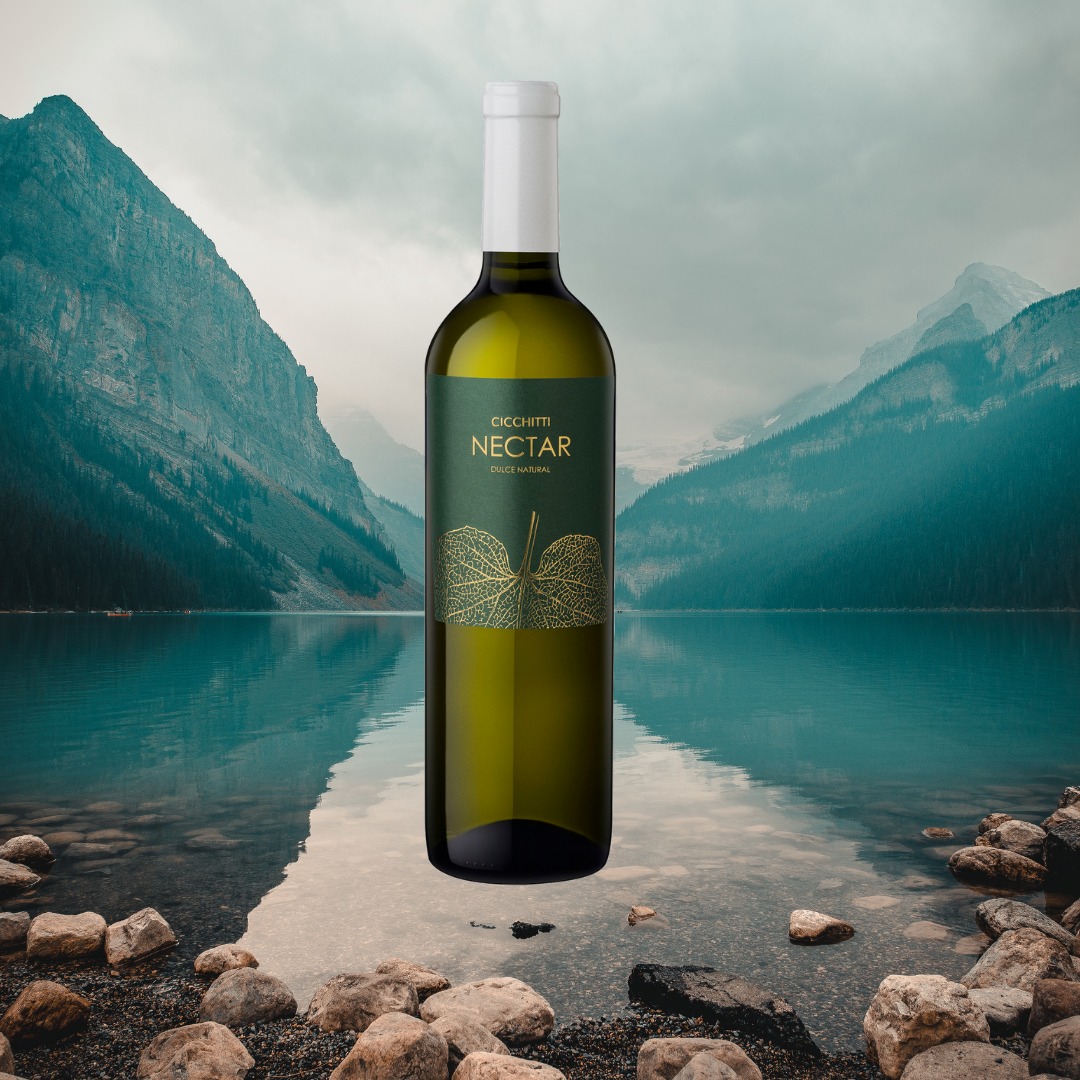 Butelka białego wina Cicchitti Nectar Dulce Natural na tle górskiego jeziora z kamienistym brzegiem.