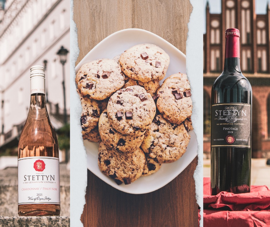 Dwie butelki wina (różowe i czerwone) marki Stettyn, obok talerza ciasteczek z kawałkami czekolady, na tle budynków.