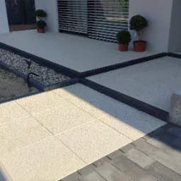 Wykończony taras z jasnych, kwadratowych płyt obramowanych ciemną kostką, z ozdobnym pasem kamieni i niskimi lampami oraz donicami z bukszpanem.