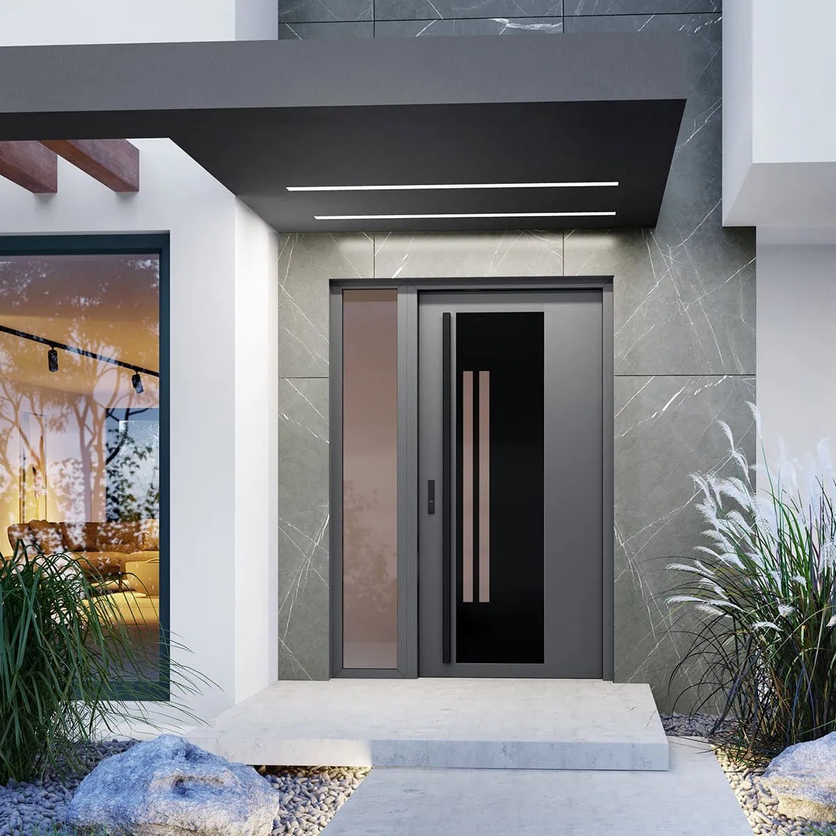 Nowoczesne drzwi wejściowe z szarym wykończeniem i bocznym panelem, osłonięte daszkiem z oświetleniem, w otoczeniu roślinności i kamieni.