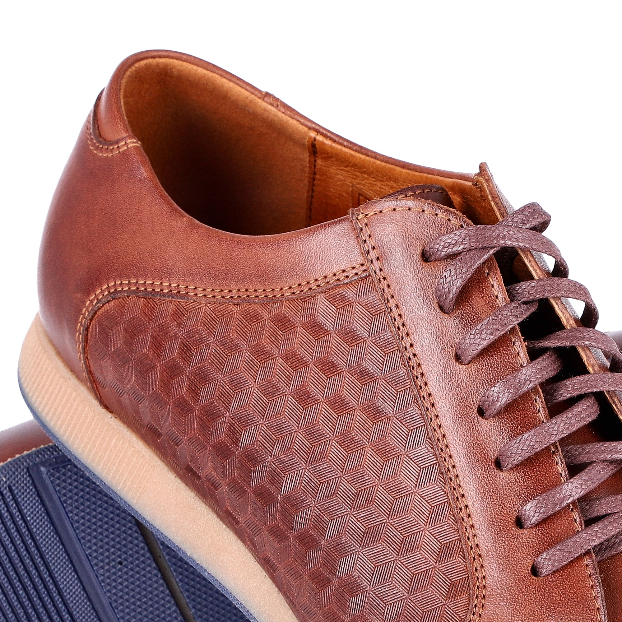 Brązowy skórzany półbut męski z wytłaczanym wzorem geometrycznym, sznurowany, z widoczną podeszwą w kolorze granatowym.