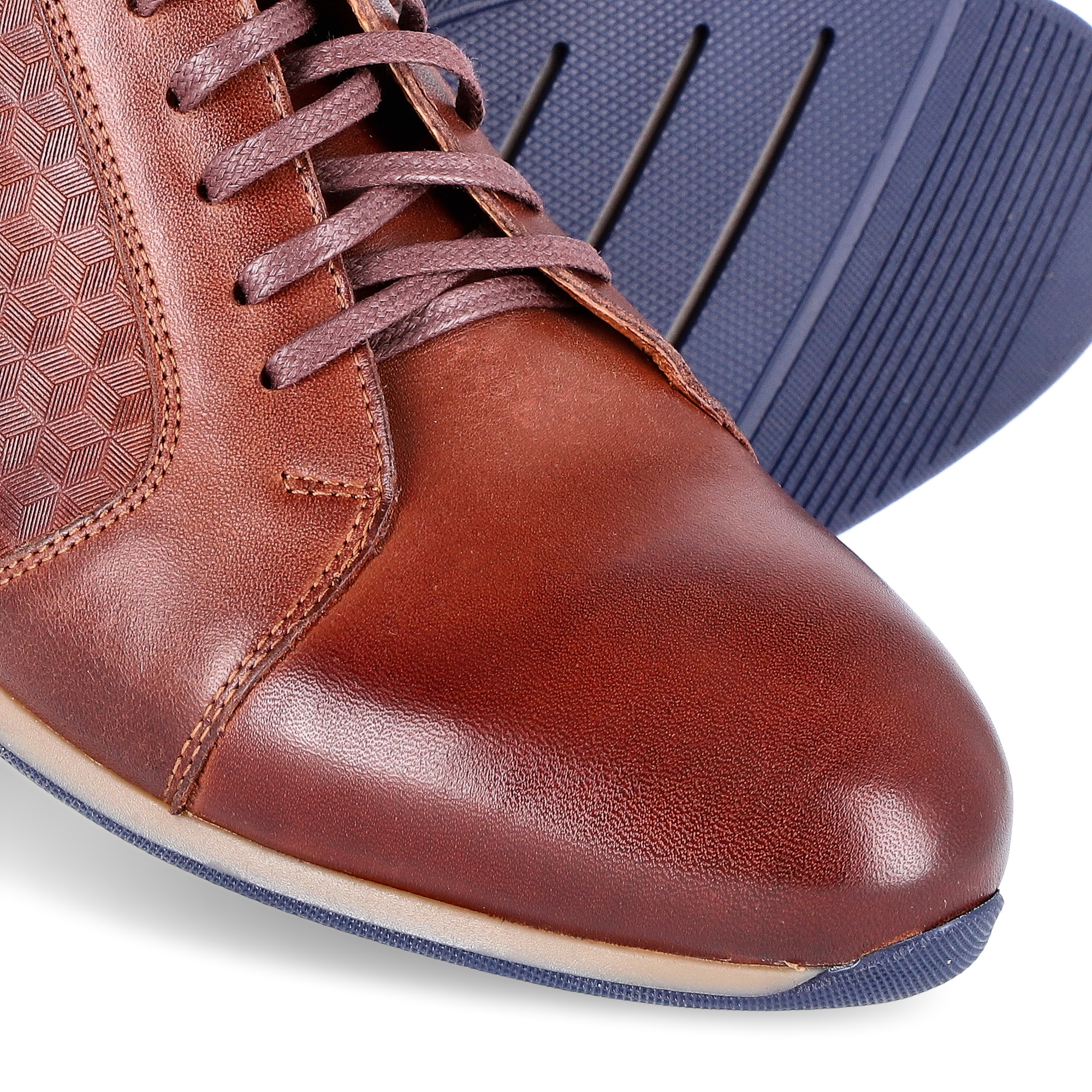 Brązowy, skórzany męski but sznurowany z ozdobnym tłoczeniem, widoczna podeszwa w kolorze granatowym.