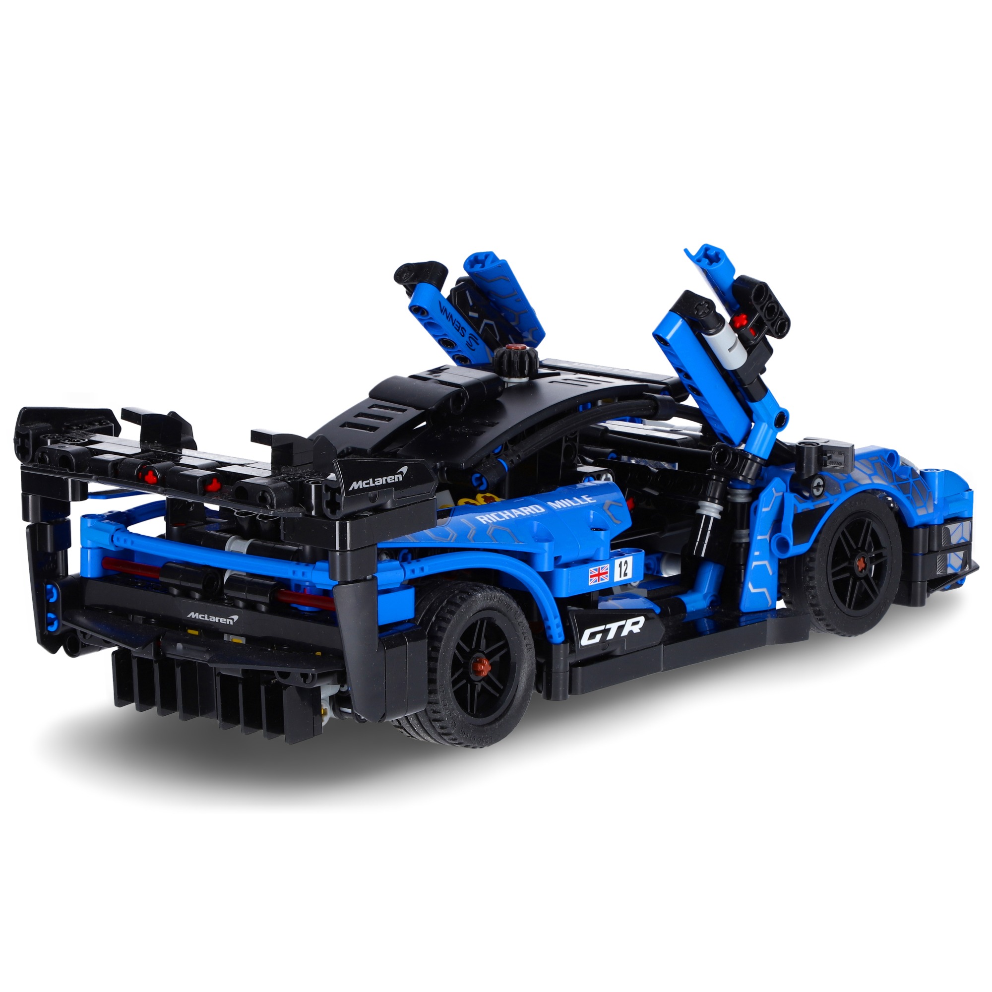 Model samochodu McLaren GTR wykonany z klocków, z otwartymi drzwiami, w kolorze niebiesko-czarnym, widoczny z perspektywy tylnego prawego koła na białym tle.