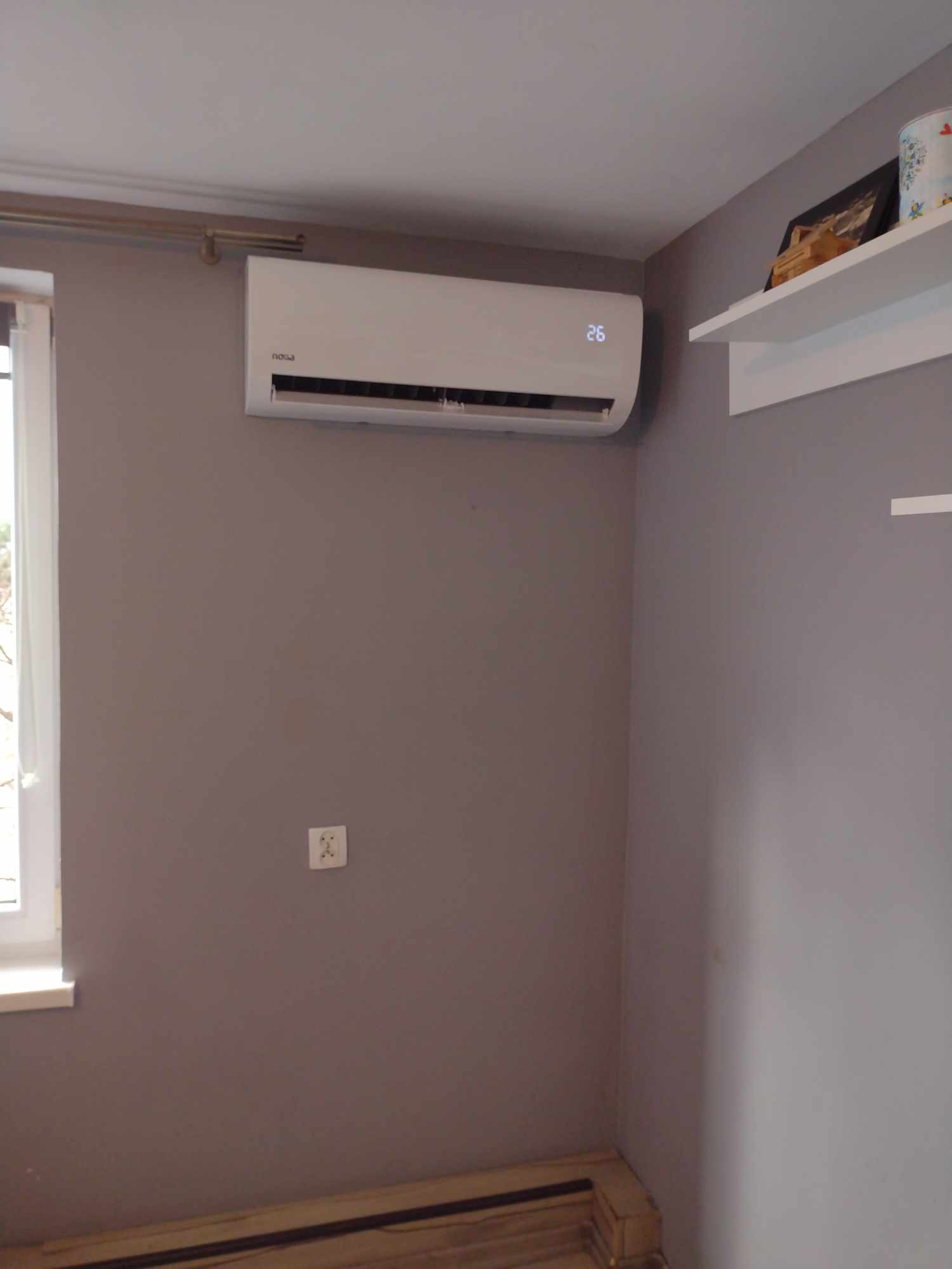 Zamontowana jednostka klimatyzacji w szarym pokoju w Żywcu, widoczny wyświetlacz temperatury 26 stopni Celsjusza i biała półka z dekoracjami.