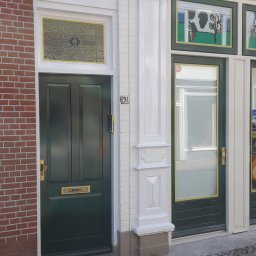 Kamil Sap Schildersbedrijf - Fasada budynku z dwoma zielonymi drzwiami, numer 29A obok jednych z nich, ceglana ściana po lewej stronie i dekoracyjne elementy architektoniczne.