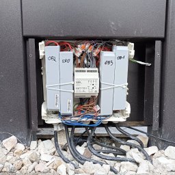 Łukasz Wojtunik Automatyka budynkowa - Otwarta skrzynka elektryczna z widocznymi przewodami, złączkami WAGO, modułami z oznaczeniami OB1, OB2, OB3, EKO i centralnym urządzeniem sterującym JUNG, całość umieszczona w ciemnej obudowie...