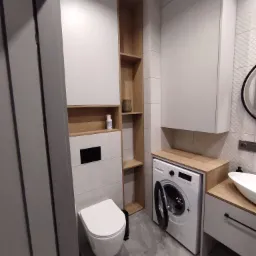 Nowoczesna łazienka z zabudową na wymiar w odcieniach szarości i drewna, z toaletą, pralką i umywalką nablatową