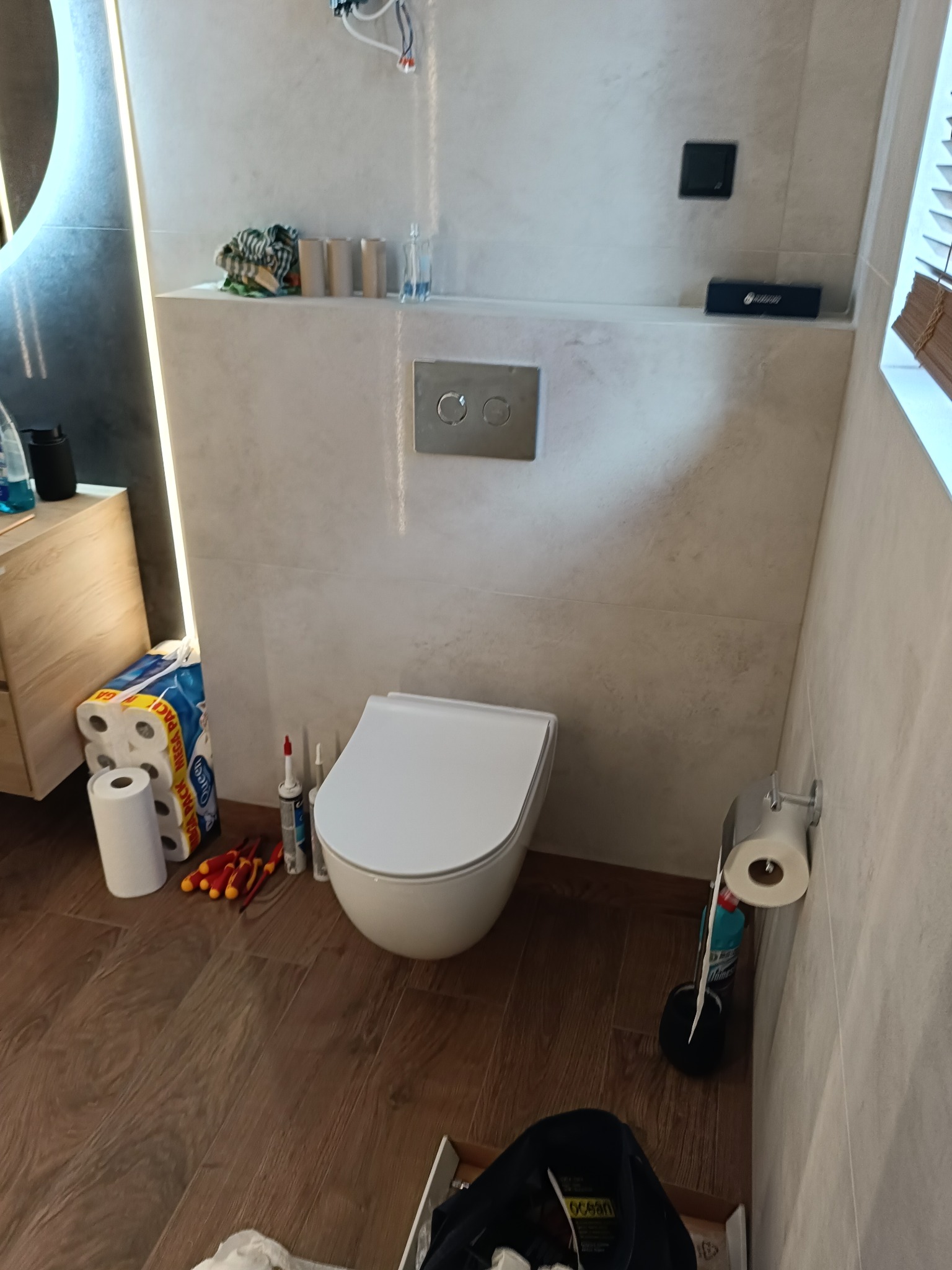 Nowoczesna toaleta podtynkowa w trakcie montażu w Białymstoku. Widoczne narzędzia, płytki imitujące kamień i elementy instalacji. Minimalistyczny design.