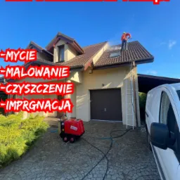 Pracownik w czerwonej kurtce myje dach domu za pomocą myjki ciśnieniowej, widoczna drabina oparta o ścianę, kostka brukowa na podjeździe, budynek z beżową elewacją, na dole reklama firmy.