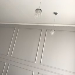 BAU FIT - Szare ściany z dekoracyjnymi listwami w ramkach i dwoma małymi, kryształowymi lampami wiszącymi