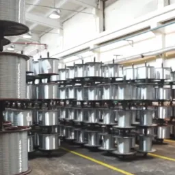 Magazyn z rzędami szpul z drutem na regałach, oświetlony światłem dziennym