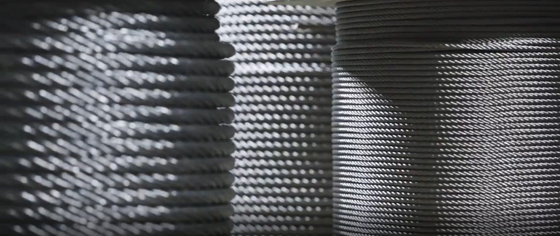 Szpule z nawiniętym sznurkiem lub liną w magazynie w Bielanach-Jarosławach, oświetlone z góry, tworzące wzór cieni.